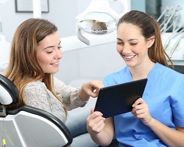 Dental team member and patient reviewing treatment plan on tablet computer