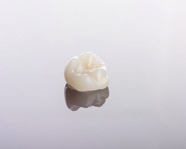 Ceramic dental crown on a reflective surface