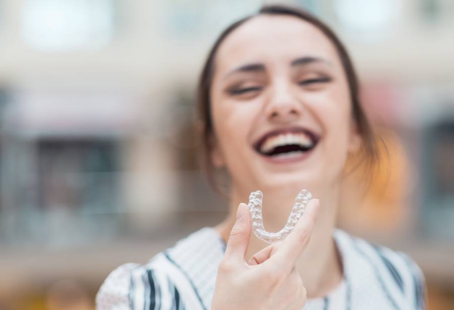 Laughing woman holding an Invisalign tray