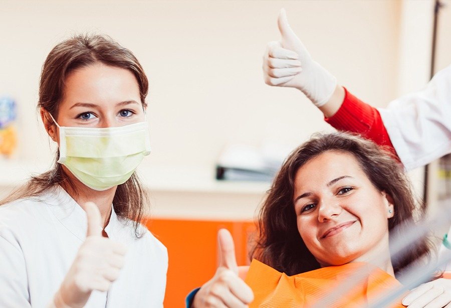 Woman and dentist giving thumbs up after tooth extraction