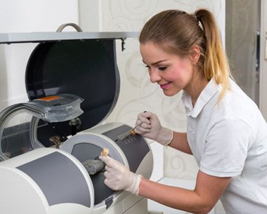 Dental team member working with CEREC milling machine.