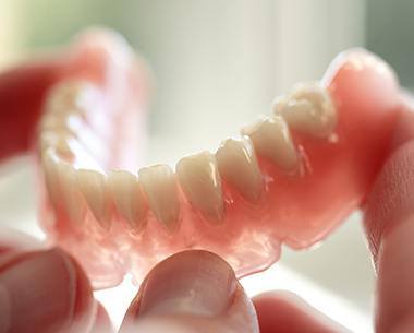 Hand holding a full denture