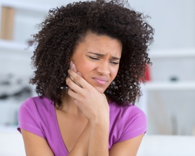 Woman in need of emergency dentistry holding jaw