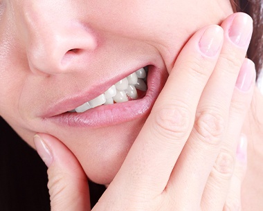 Closeup of patient in pain holding jaw before tooth extraction