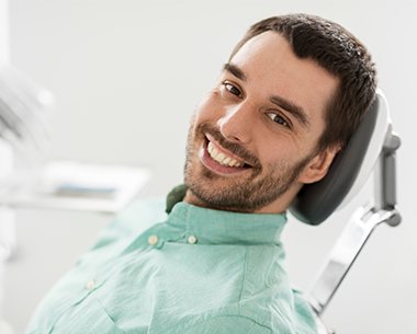 Man in dental chair smiling after tooth extraction