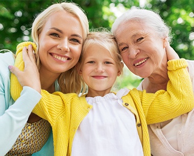 Three generations of women smiling together after family dentistry