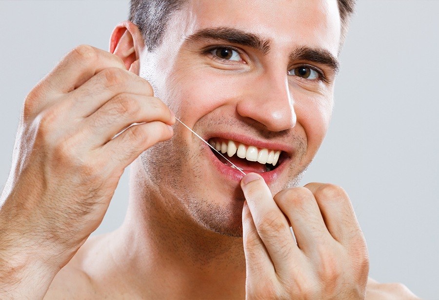 Man flossing teeth after periodontal disease treatment