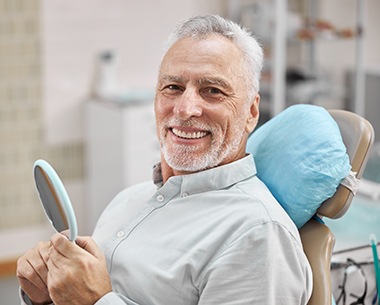 Man smiling after dental implant supported denture restoration