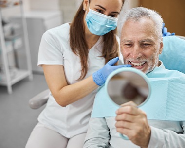 Man looking at smile after dental implant retained prosthetics