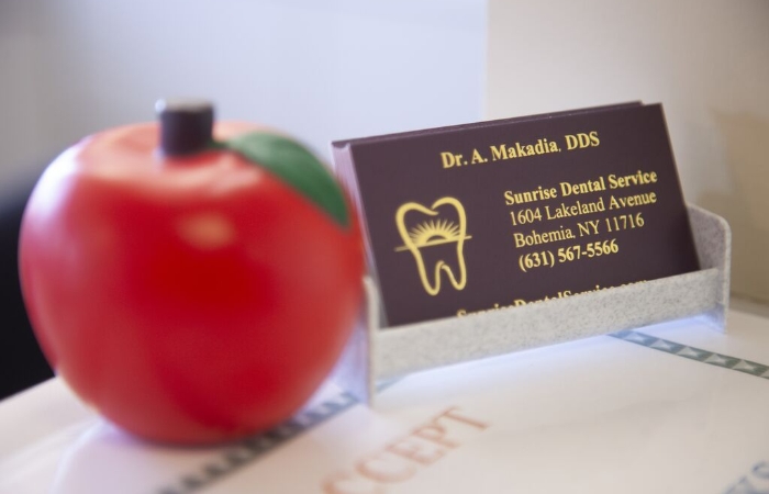 Doctor Makadia's buisness card and an apple on the dental office reception desk