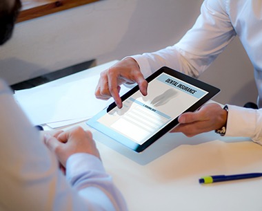 Dentist and patient looking at dental insurance claims on tablet computer