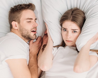 Frustrated woman next to snoring man in need of NightLase treatment