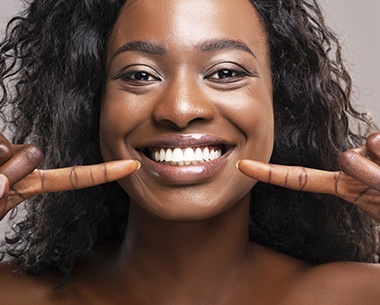 Woman pointing to smile after laser gum pigmentation removal