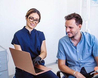 Patient and dental team member looking at computer