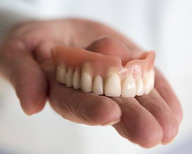 Hand holding full denture