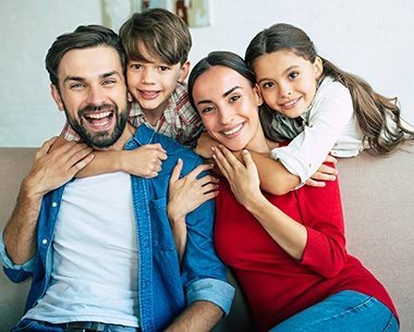 Mother father and two children smiling after family dentistry