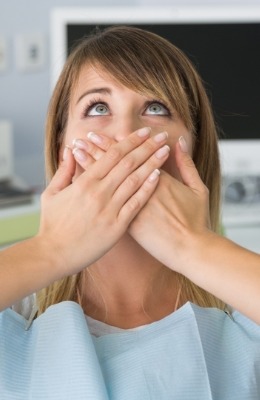 Fearful patient in need of sedation dentistry covering her mouth