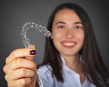 Woman holding up a SureSmile aligner