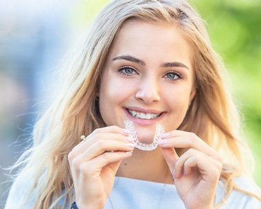 Smiling woman placing her SureSmile aligner