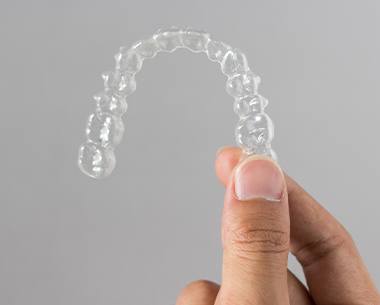 Hand holding up a SureSmile aligner tray