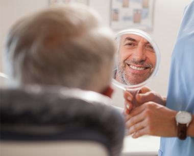 Man looking at smile after treatment with ceramic tooth sparing burs