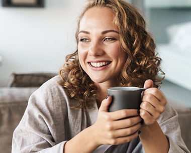 Woman drinking a cup of coffee after tooth colored filling restoration