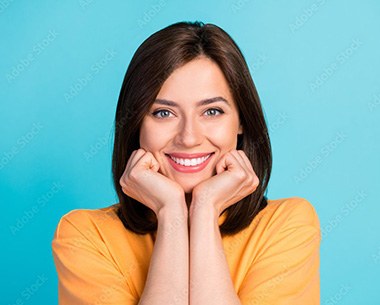 Woman with hands on her chin showing off a beautiful smile thanks to veneers