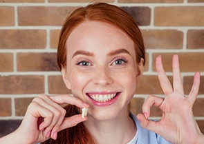 Woman smiling and holding up her tooth after a simple wisdom tooth extraction