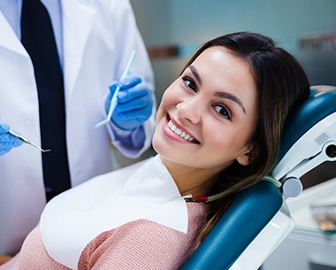 Woman in dental chair smiling following her wisdom tooth extraction