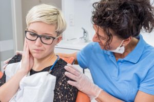 woman with a toothache sitting in chair at her dentist