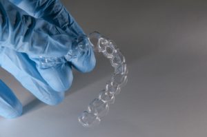 Gloved hand holding clear aligner