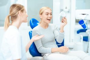 Satisfied patient using mirror to admire the results of her cosmetic treatment