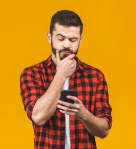 Man looking at phone, searching for a good dentist