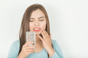 Woman sipping ice water, concerned about sensitive teeth