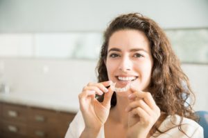 Smiling woman holding clear aligner