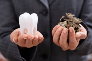 Female hands holding large tooth and coins