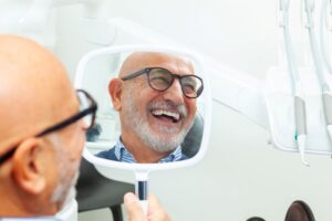 Dental patient's smiling face reflected in hand mirror