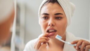Concerned woman looking at her mouth in mirror 