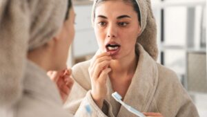Concerned young woman looking at her gums in mirror